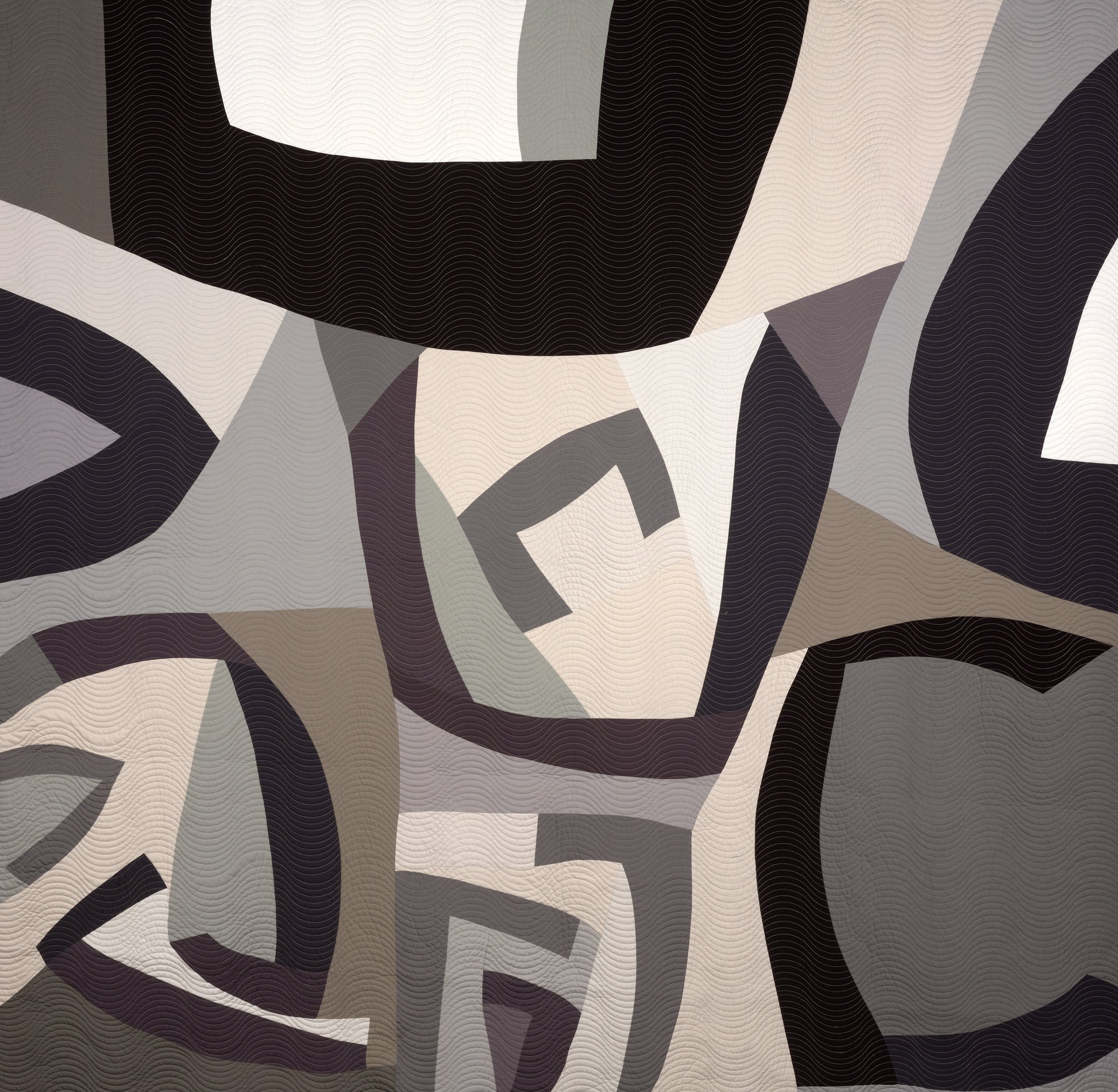Abstract patterned quilt with geometric shapes in black, gray, and white.